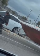 Man in motorized wheelchair tows a powerboat through Cali intersection