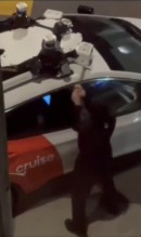 Masked person destroys a Cruise AV with a hammer