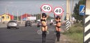 Two girls holding speed limits signs