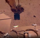 NASA InSight's robotic arm scoops up sand to trickle it above its solar panels