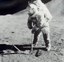 Apollo 15 astronaut Jim Irwin uses a scoop to collect soil samples on the lunar surface