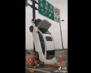 White sedan crashes into barrier, ends up propped against a pole