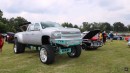 Lifted Chevrolet dually pickup truck has teal accents and custom bed with three TVs on WhipAddict