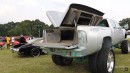 Lifted Chevrolet dually pickup truck has teal accents and custom bed with three TVs on WhipAddict