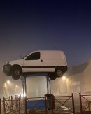 A white van showed up perched on top of a bus shelter, and no one knew how it got there