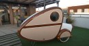 DIY bike trailer doubles as snug bedroom for one adult, has storage, lights, and charging outlets