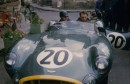 Tony Brooks parked outside the 1957 Le Mans Aston Martin base, the Hotel de France, at the wheel of his DBR1 race car.
