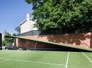 Wayne Residence hides a 12-car garage under the tennis court, styled after the Batcave