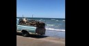 Vintage Ford truck captured exiting the ocean with wood load