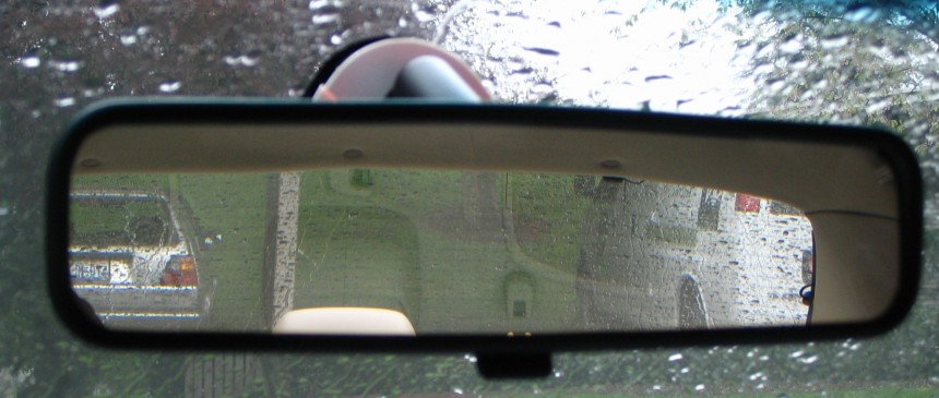 Rear\-view mirror showing cars parked behind the vehicle containing the mirror
