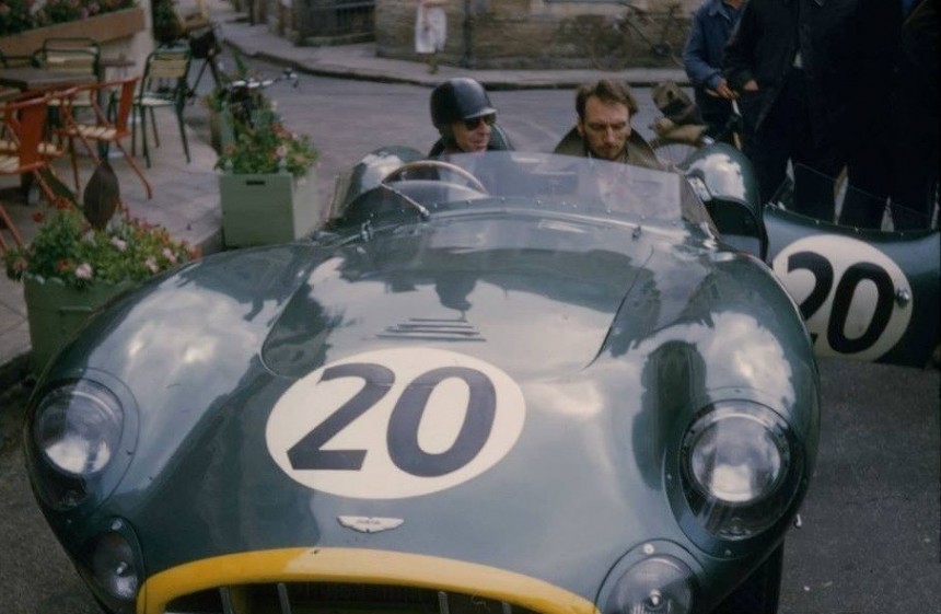 Tony Brooks parked outside the 1957 Le Mans Aston Martin base, the Hotel de France, at the wheel of his DBR1 race car\.