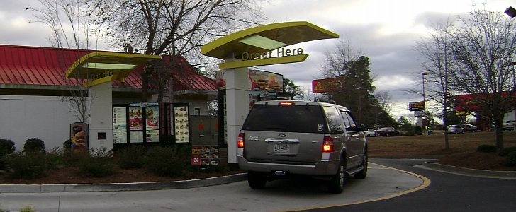 An SUV stopped at the ordering booth of a McDonald's drive-thru
