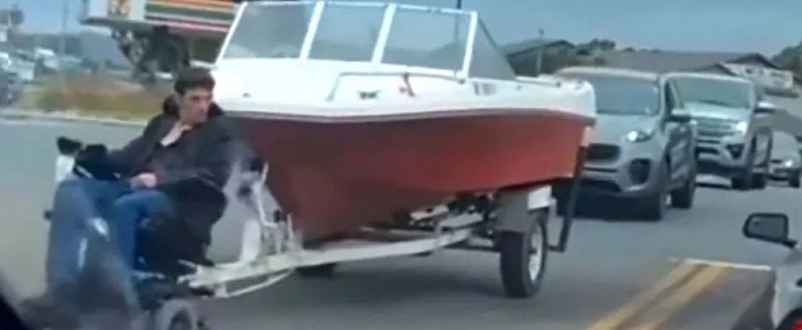 Man in motorized wheelchair tows a powerboat through Cali intersection