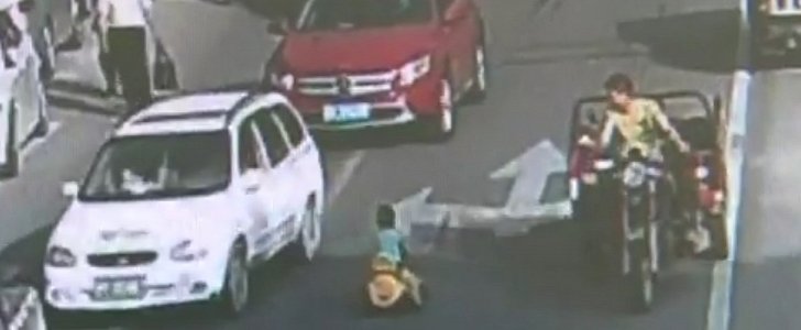 Toddler rides toy vehicle in traffic