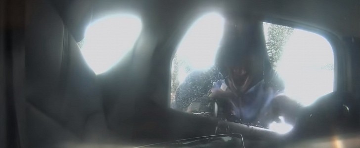 Thief breaking the rear window of a vehicle
