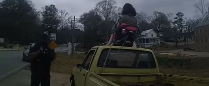 Cops check on Borat sitting in a parked pickup, with his daughter strapped to the roof