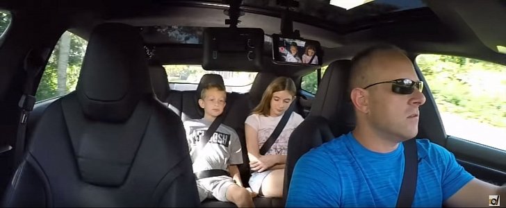 Two kids sitting in the back of a Tesla Model S