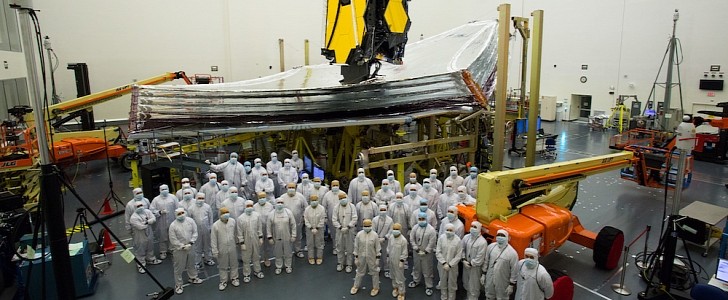 Technicians and engineers pose in front JWST