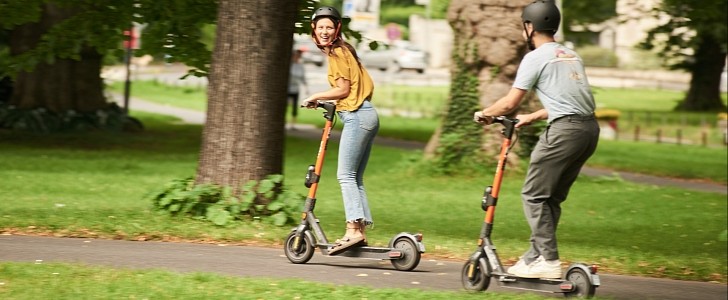 Two people riding rental e-scooters