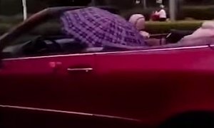 Man Holds Umbrella While Driving Mercedes CLK in The Rain