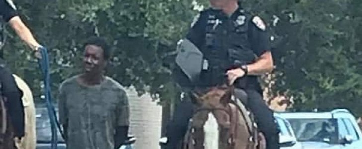 Homeless man is led by a rope by two white mounted police officers