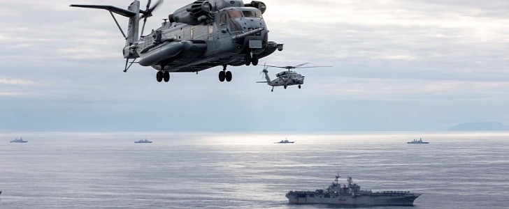 USS Iwo Jima (LHD 7) is accompanied by a CH-53E Super Stallion helicopter and an MH-60S Sea Hawk helicopter 