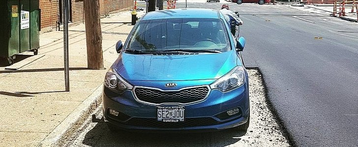 A parked Kia gets in the way of road repairs, workers ignore it
