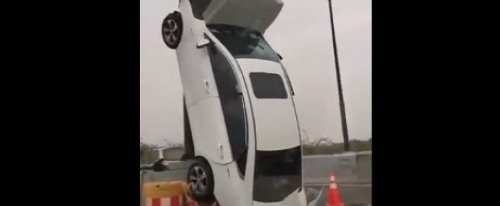 White sedan crashes into barrier, ends up propped against a pole