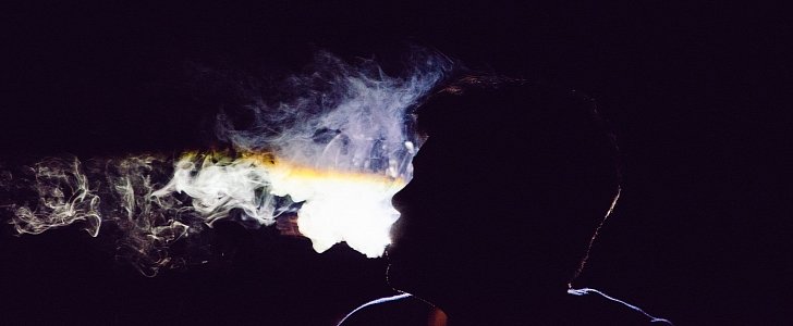 Person exhaling smoke in the dark