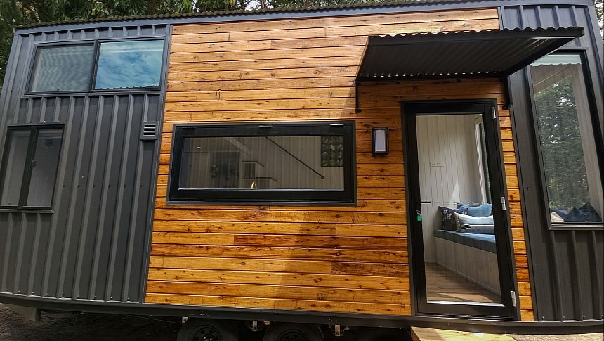 The Little Wren is a cabin-like tiny home with one loft bedroom and blue accents