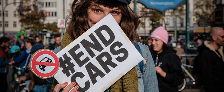 Person holding sign that writes "#ENDCARS" at a protest in Berlin