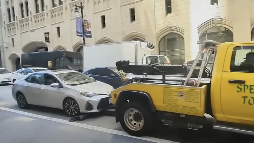 Tow truck driver tries to hook Toyota Corolla in traffic