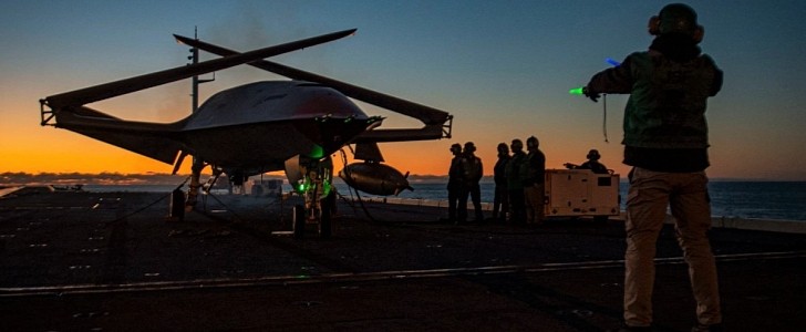 A Boeing unmanned MQ-25 aircraft is given operating directions on the flight deck aboard the aircraft carrier USS George H.W. Bush 