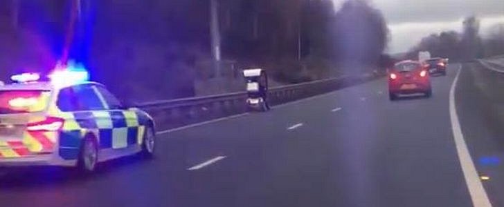 Police cruiser slowly pursues mobility scooter down dual carriageway in Wales, U.K.